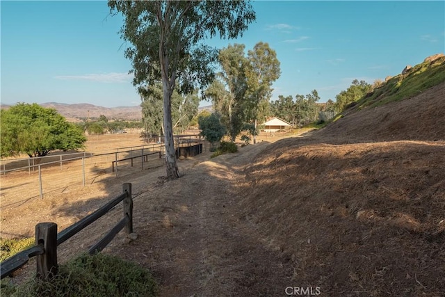 view of yard with a rural view, fence, and a mountain view