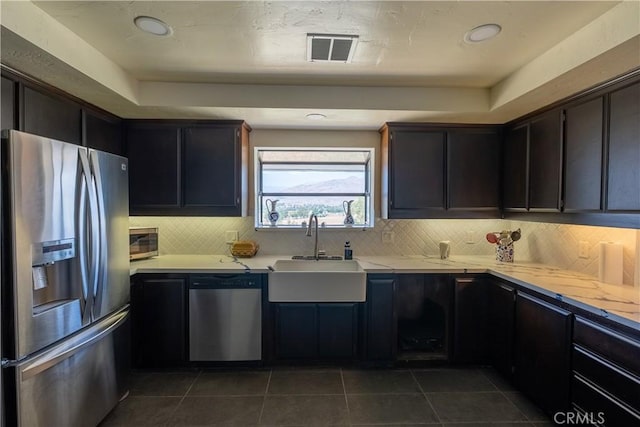 kitchen featuring stainless steel appliances, visible vents, a sink, and decorative backsplash