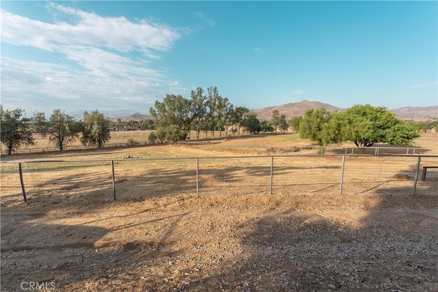 view of yard featuring fence, a mountain view, and a rural view