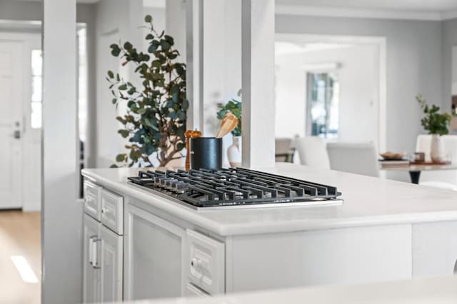 kitchen featuring crown molding, stainless steel gas cooktop, and white cabinets