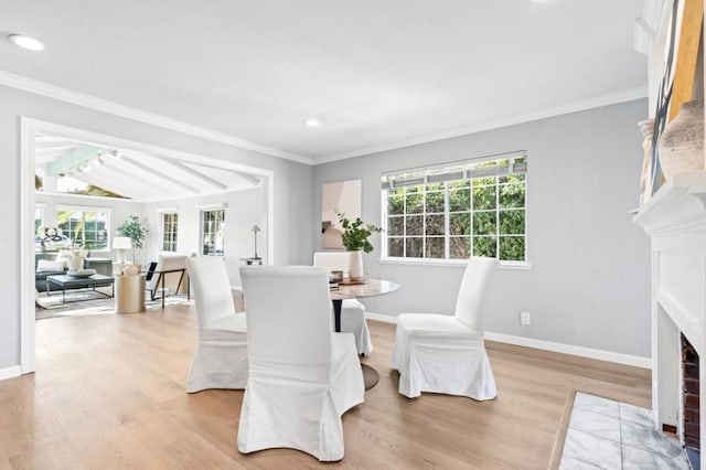 dining space featuring crown molding, vaulted ceiling, and light wood-type flooring