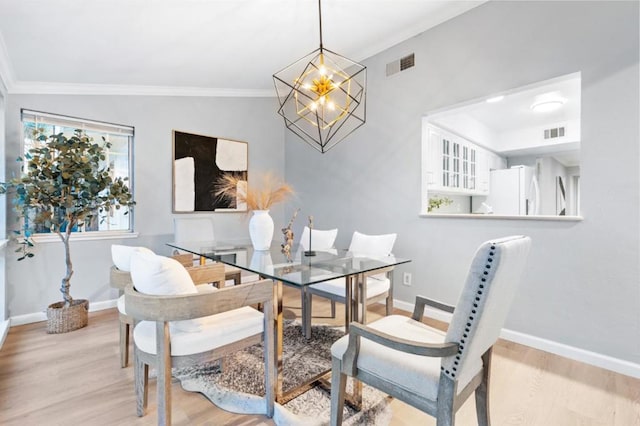 dining room featuring crown molding, a notable chandelier, and light hardwood / wood-style floors