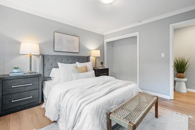 bedroom with light hardwood / wood-style flooring, ornamental molding, and a closet