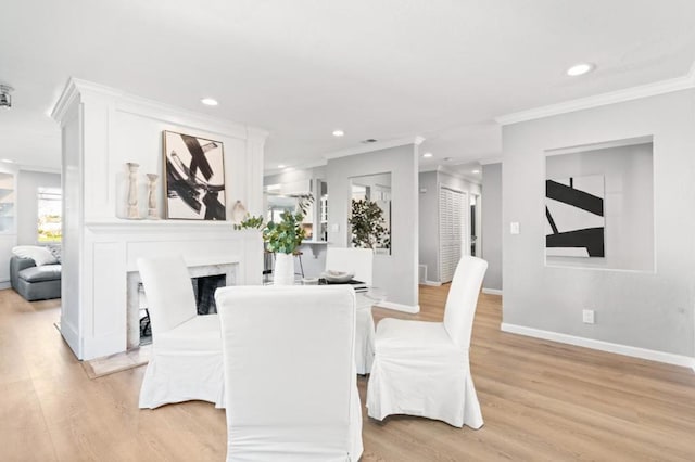 dining area featuring light hardwood / wood-style flooring, ornamental molding, and a premium fireplace