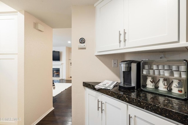 bar featuring white cabinets, dark hardwood / wood-style flooring, and dark stone counters