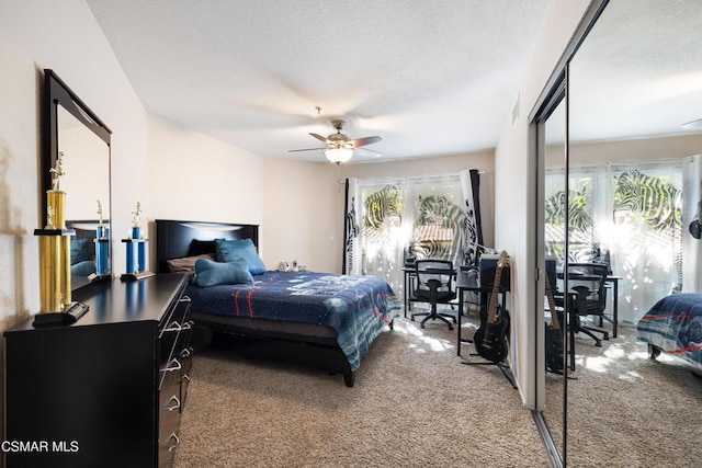 carpeted bedroom featuring ceiling fan and a textured ceiling