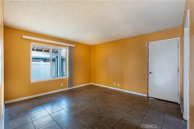 empty room with dark tile patterned floors and a textured ceiling