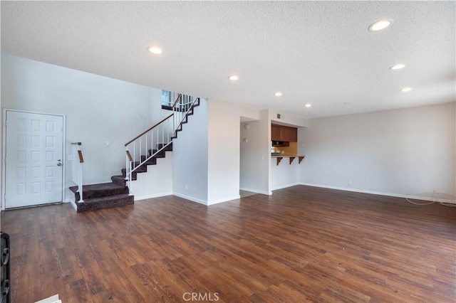 unfurnished living room featuring a textured ceiling and dark hardwood / wood-style flooring