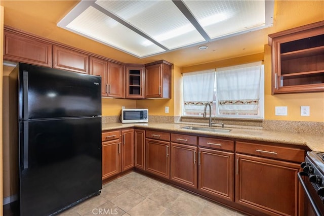 kitchen with sink, light tile patterned floors, and black appliances