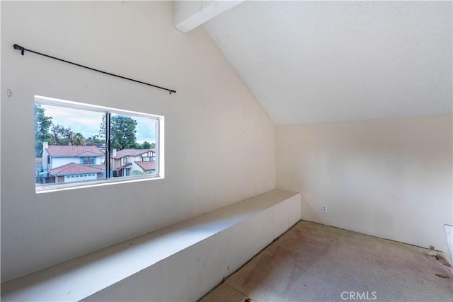 additional living space featuring light carpet and vaulted ceiling with beams