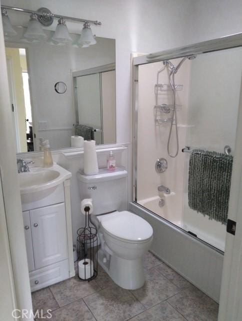 full bathroom featuring vanity, tile patterned flooring, shower / bath combination with glass door, and toilet