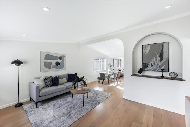 living room featuring lofted ceiling with beams, ornamental molding, and light hardwood / wood-style floors