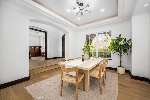 dining space featuring a chandelier, light hardwood / wood-style floors, and a tray ceiling