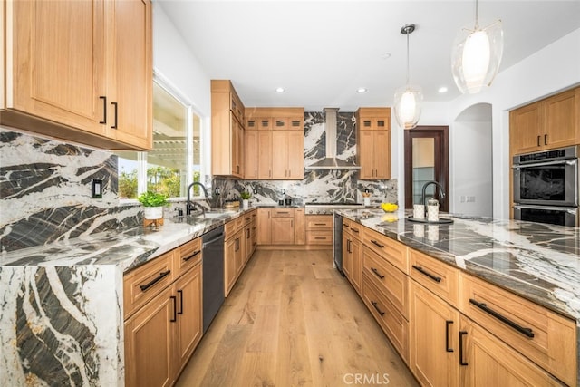 kitchen with sink, stone countertops, appliances with stainless steel finishes, pendant lighting, and wall chimney range hood