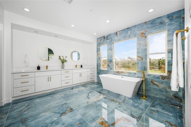 bathroom with vanity, a bath, and tile walls