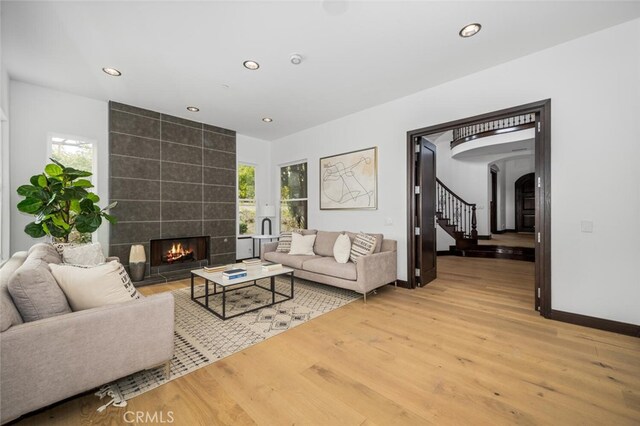 living room with wood-type flooring and a tiled fireplace