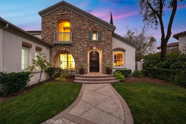 view of front of house with a balcony and a yard