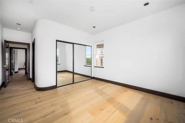 unfurnished bedroom with light wood-type flooring and a closet