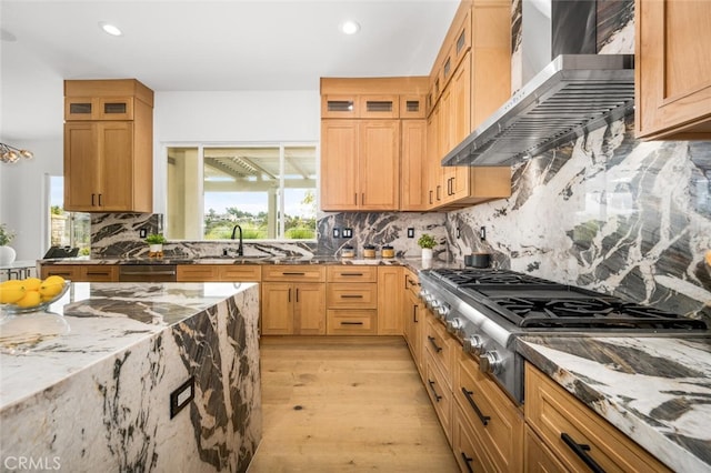 kitchen with stainless steel gas stovetop, tasteful backsplash, sink, light stone countertops, and wall chimney exhaust hood