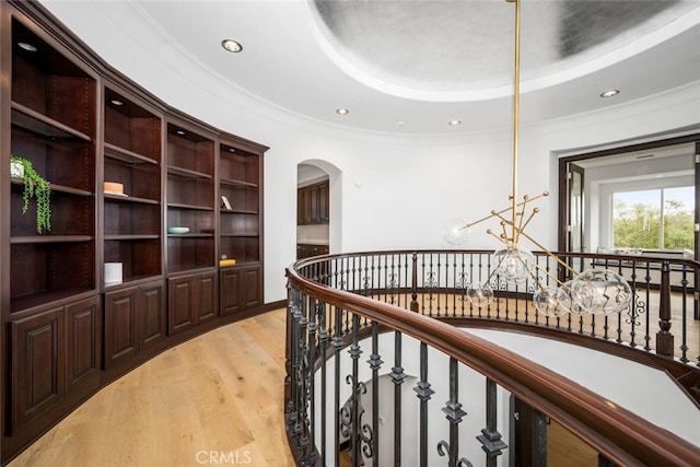 hallway featuring a tray ceiling, crown molding, and light wood-type flooring