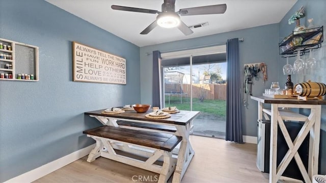 dining space with ceiling fan and light wood-type flooring