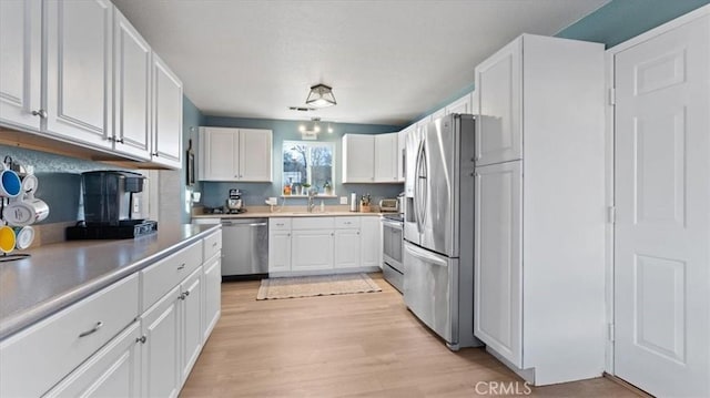 kitchen featuring white cabinetry, appliances with stainless steel finishes, sink, and light wood-type flooring