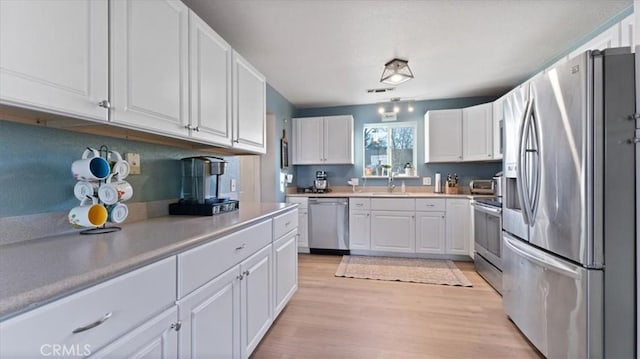 kitchen featuring white cabinetry, stainless steel appliances, and light hardwood / wood-style floors