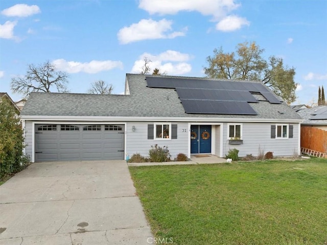 front of property featuring a garage, a front yard, and solar panels