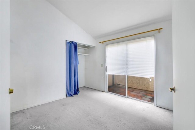 unfurnished bedroom with light colored carpet, lofted ceiling, and a closet