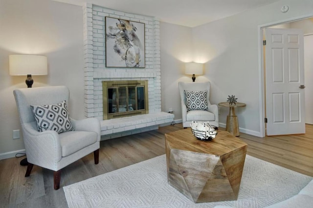 sitting room with wood-type flooring and a brick fireplace