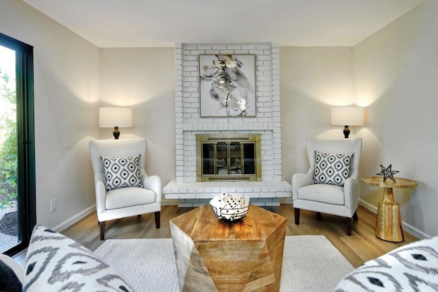 living room with a brick fireplace and hardwood / wood-style flooring