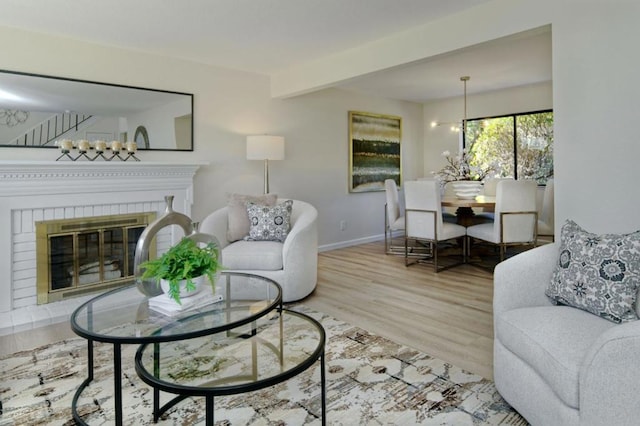 living room with hardwood / wood-style flooring, a fireplace, a chandelier, and beam ceiling