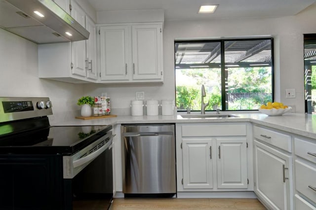 kitchen with appliances with stainless steel finishes, sink, white cabinets, and light hardwood / wood-style floors