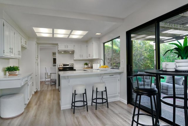 kitchen with sink, light hardwood / wood-style flooring, a breakfast bar, white cabinetry, and kitchen peninsula