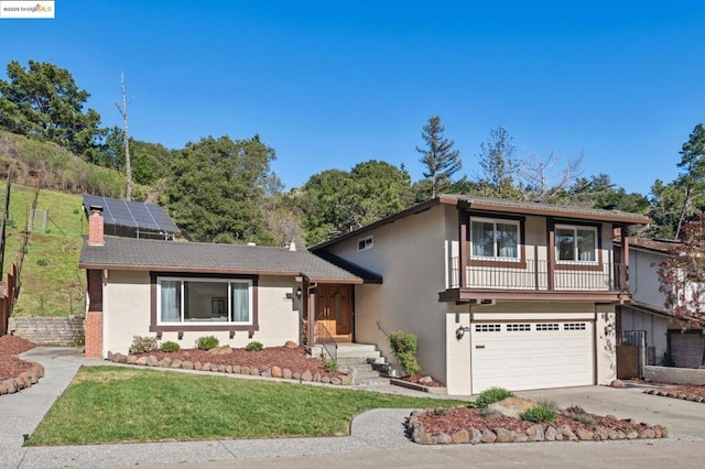 split level home featuring a garage, a front yard, and solar panels