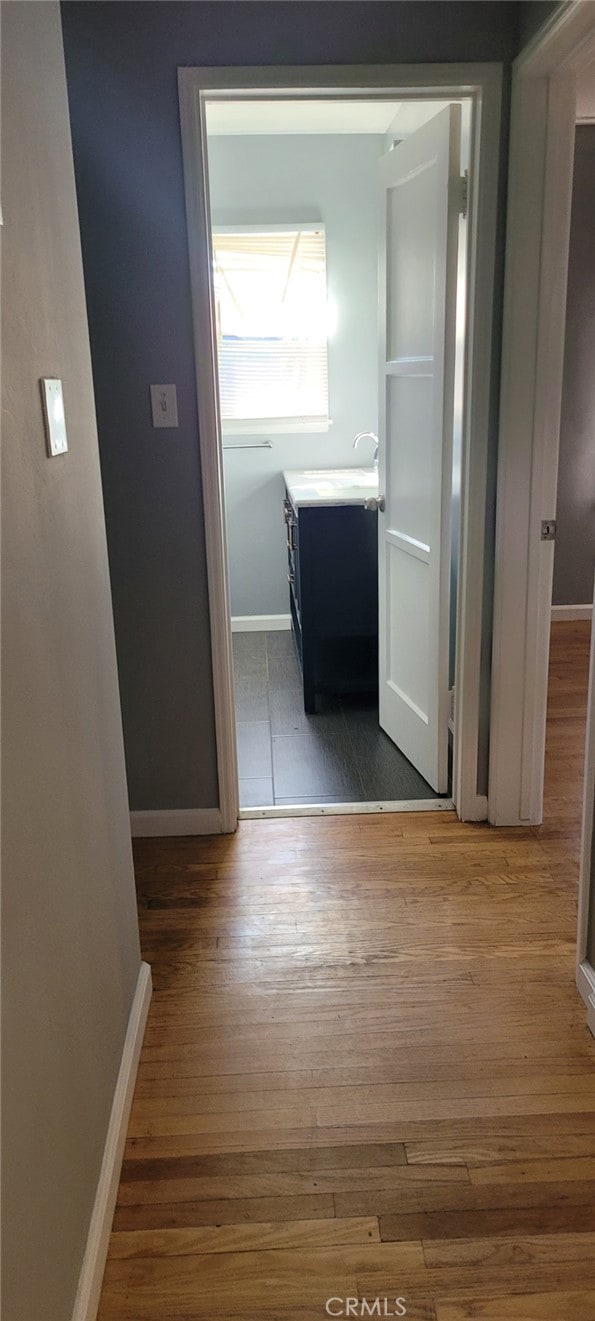 corridor featuring baseboards and wood finished floors