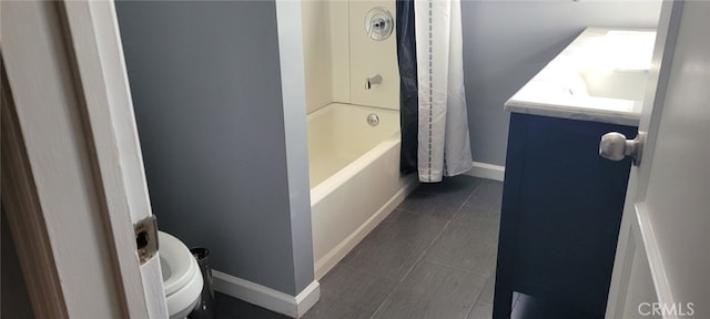 bathroom featuring tile patterned flooring, toilet, vanity, baseboards, and shower / bath combo