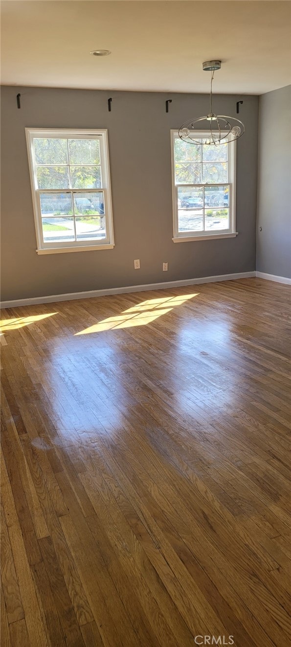 spare room featuring a healthy amount of sunlight, baseboards, and dark wood-style flooring