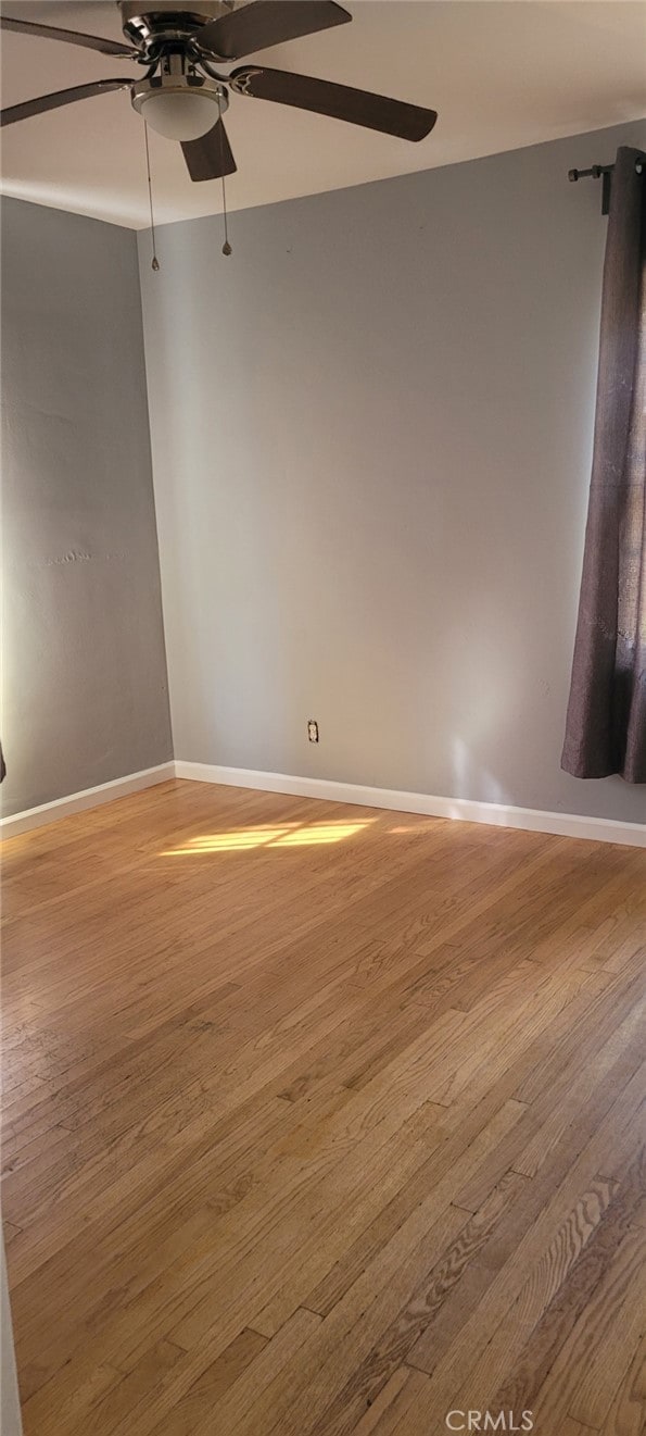 spare room with ceiling fan, baseboards, and wood finished floors