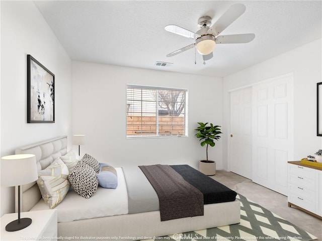 bedroom featuring light carpet, a ceiling fan, visible vents, and a closet