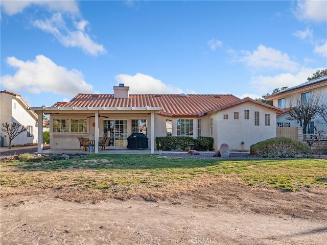 rear view of property featuring a tile roof, a chimney, stucco siding, a patio area, and fence