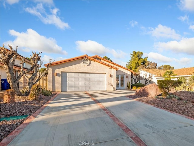 mediterranean / spanish-style house with concrete driveway, an attached garage, a tiled roof, and stucco siding