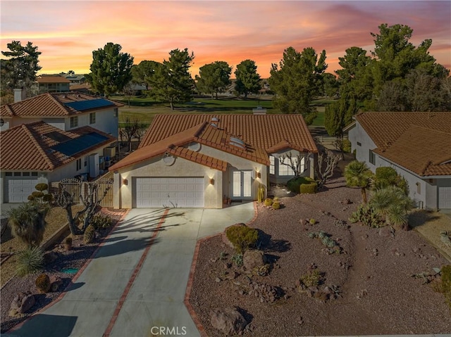 view of front of home featuring a garage, driveway, a tile roof, and stucco siding