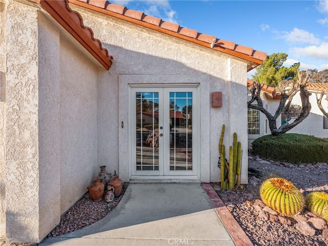 view of exterior entry featuring french doors, a patio area, and stucco siding