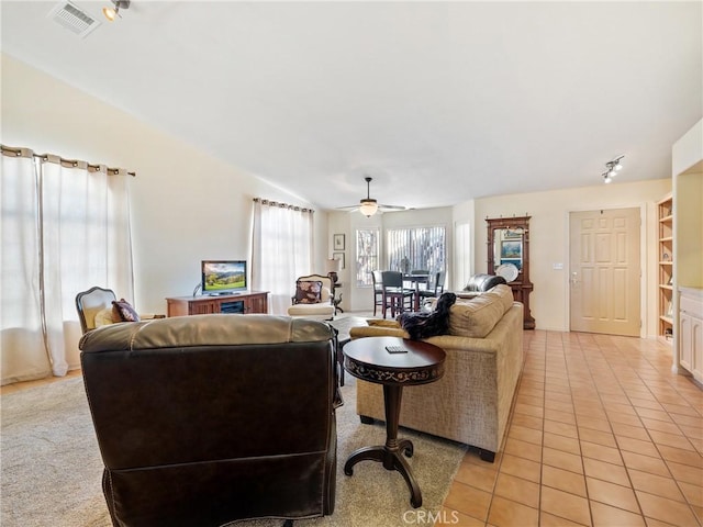 living room featuring light tile patterned floors, lofted ceiling, visible vents, and a ceiling fan