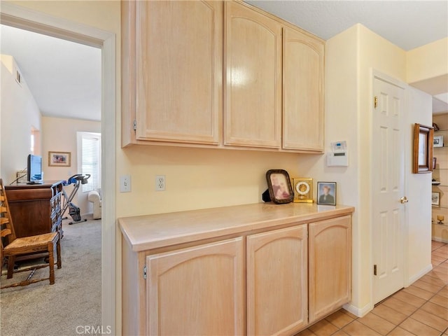 kitchen featuring light tile patterned floors, light carpet, visible vents, light countertops, and light brown cabinetry