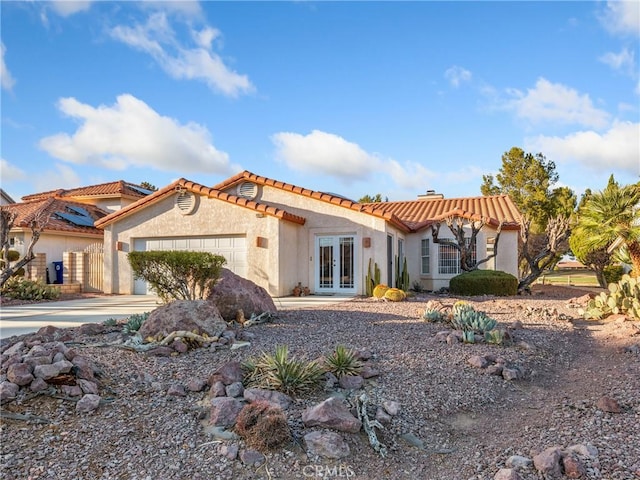 view of front of home with an attached garage, driveway, french doors, stucco siding, and a chimney