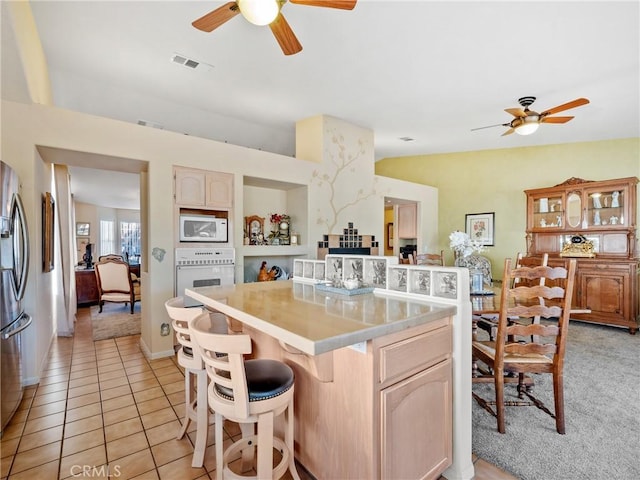 kitchen featuring light tile patterned floors, light countertops, visible vents, ceiling fan, and white appliances