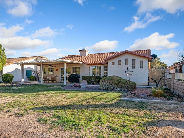 rear view of property with a chimney, fence, a lawn, and a patio