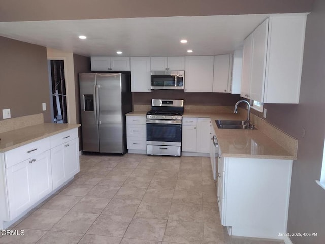 kitchen with sink, light tile patterned flooring, white cabinets, and appliances with stainless steel finishes